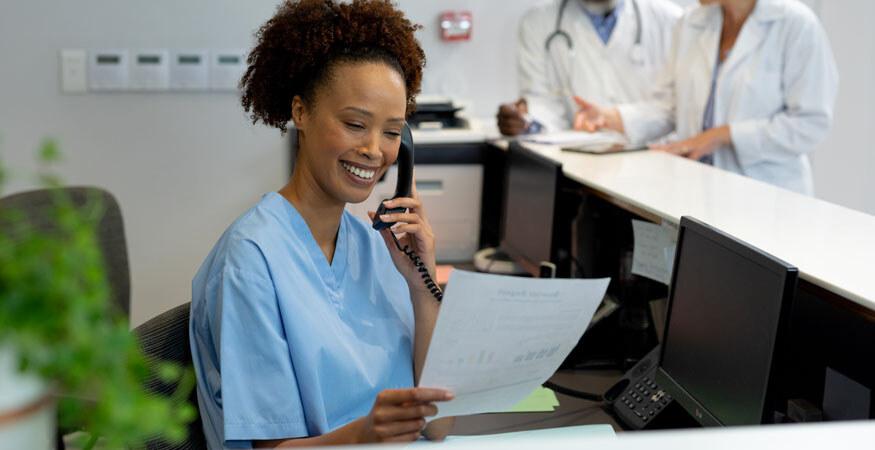 Healthcare worker looking at a document printed on a fax machine